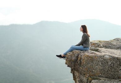 A woman sits on the edge of a cliff A woman sits on the edge of a cliff