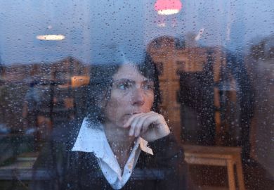A woman looks out of a rain-splashed window, illustrating genderwashing