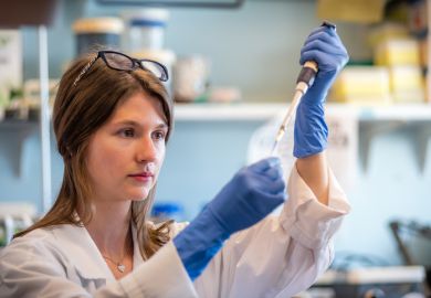 Woman researcher in biotechnology laboratory pipetting genetic material