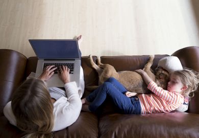 Woman using laptop while daughter and dog sleep
