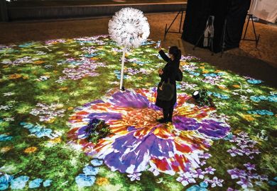 A woman uses her smartphone in an interactive multimedia installation that connects Singapore and Japan in a time of separation, in Tokyo on November 13, 2020 A woman uses her smartphone in an interactive multimedia installation that connects Singapore and Japan in a time of separation, in Tokyo on November 13, 2020