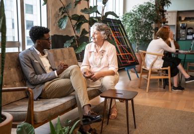 Young black university student being mentored by a mature woman in the workplace, illustrating that work placements can improve graduate employability.