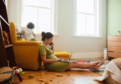 Working mother taking a phone call in her son's play area