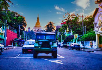Yangon, Myanmar - December 02 2012  a military jeep on street of Yangon Myanmar and a Pagoda in the background