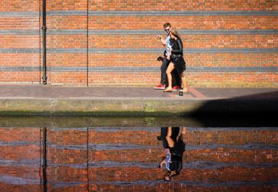 Young couple walking along canal with reflection on water