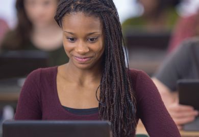 Young female student smiling and looking at computer monitor