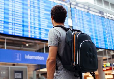 Young man looking at airport departures board
