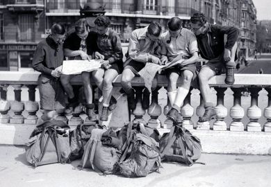 Young men sitting on a wall looking at maps