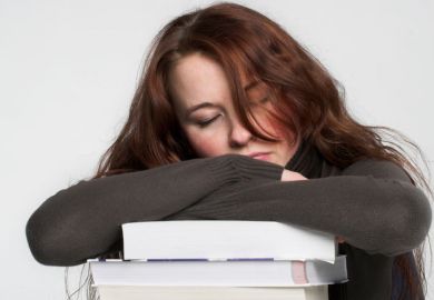 Young woman asleep on pile of books