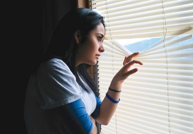 Young woman peeking through venetian blinds