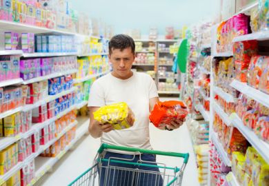 Young caucasian man make choose between two similar goods. Shopping in supermarket or grocery