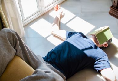 Young man resting on the floor with a book on his face Young man resting on the floor with a book on his face