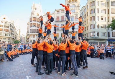 Young members of moixiganga group forming human tower on the street festival in Valencia