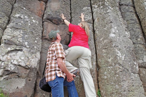 A man giving a women a leg up to climb a cliff A man giving a women a leg up to climb a cliff