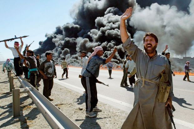 Armed Iraqi fighters standing on smoke-covered road Armed Iraqi fighters standing on smoke-covered road