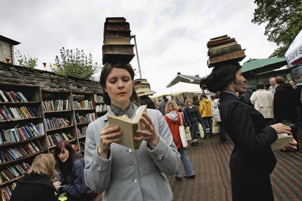 People balancing books on their heads at the Hay Literary Festival. To illustrate librarians needing to discard underused books due to lack of shelf space. People balancing books on their heads at the Hay Literary Festival. To illustrate librarians needing to discard underused books due to lack of shelf space.
