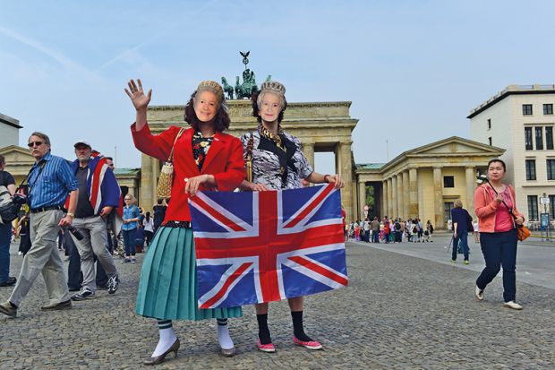 Pair wearing queen masks and holding Union Jack in front of Brandenburg Gate Pair wearing queen masks and holding Union Jack in front of Brandenburg Gate