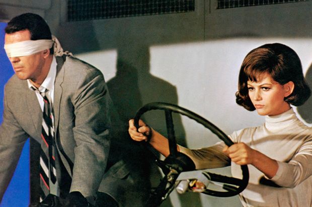 Film still from "Blindfold", showing man wearing a blindfold next to a woman driving, 1965. To illustrate a lack of supervision or monitoring during some remote assessments in UK universities 