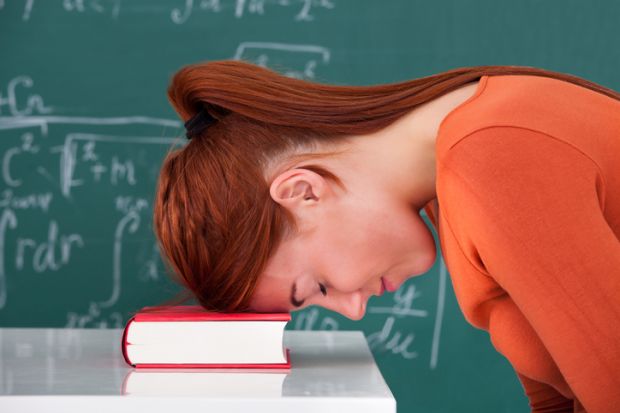 A bored academic leans her head on a book