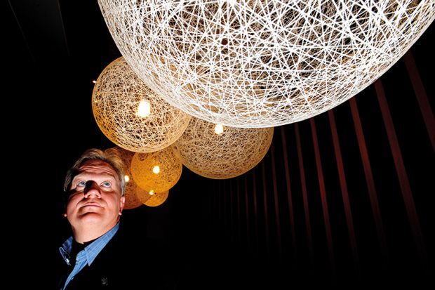 Nobel laureate Brian Schmidt looking up at lit up spheres Nobel laureate Brian Schmidt looking up at lit up spheres