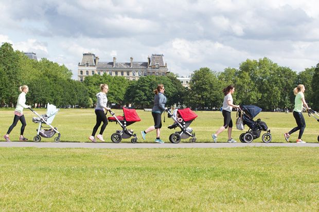 Women push children’s buggies across a park Women push children’s buggies across a park