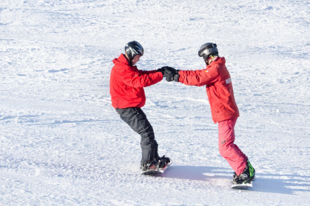BUKOVEL, UKRAINE- 27 JANUARY 2018: Instructor teaches a guy to ride a snowboard
