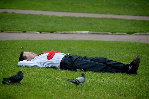 Sleeping businessman in a park on his lunch break, illustrating that employers are taking a back seat with regard to funding higher education. 