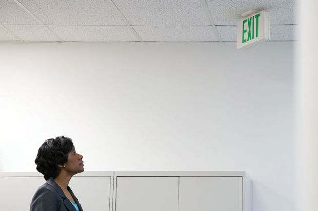 Businesswoman looking up at office 'Exit' sign Businesswoman looking up at office 'Exit' sign