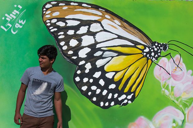 Man in front of a painted butterfly on a wall, Iran Man in front of a painted butterfly on a wall, Iran