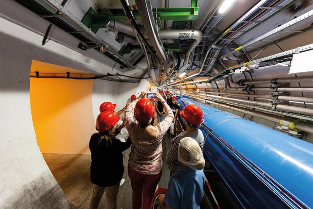 People in hard hats in tunnel at CERN lab People in hard hats in tunnel at CERN lab