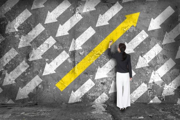 Someone colours a large arrow in yellow on a wall - it's pointing in the opposite direction to a number of smaller white arrow Change direction