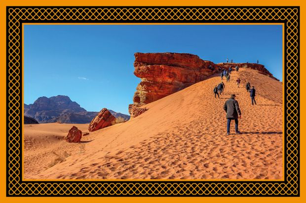 people climb the dunes in Wadi Rum desert at the top of red rock, Jordan