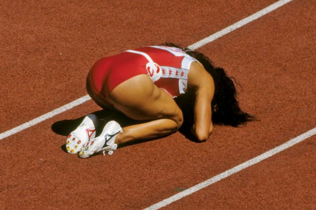 Competitive sprinter kneeling on race track Competitive sprinter kneeling on race track