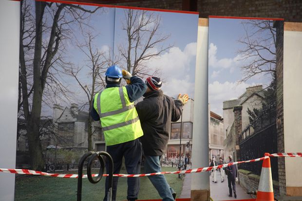 Construction workers installing hoarding around a property development site, to illustrate that universities must choose between physical or digital development. Construction workers installing hoarding around a property development site, to illustrate that universities must choose between physical or digital development.