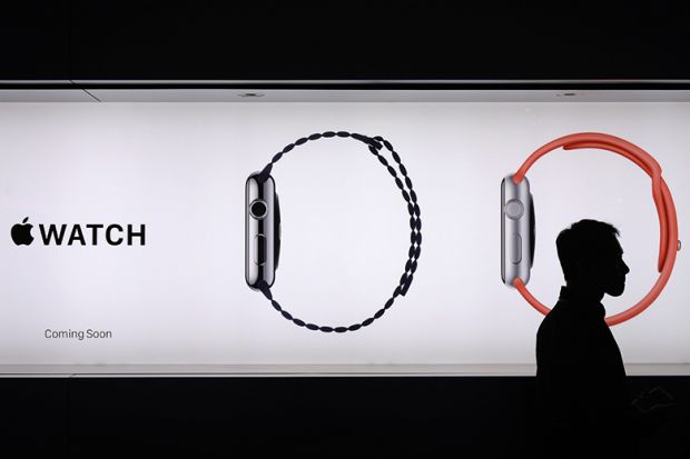 A man walks past a billboard ad for Apple watches, his head encircled by one of the images A man walks past a billboard ad for Apple watches, his head encircled by one of the images