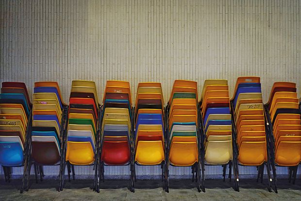 Colourful set of chairs piled up by a wall Colourful set of chairs piled up by a wall