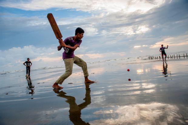 Boys play cricket on the beach Boys play cricket on the beach