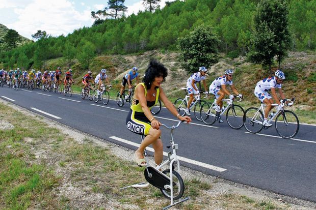 Woman on stationary bike next to cycle race