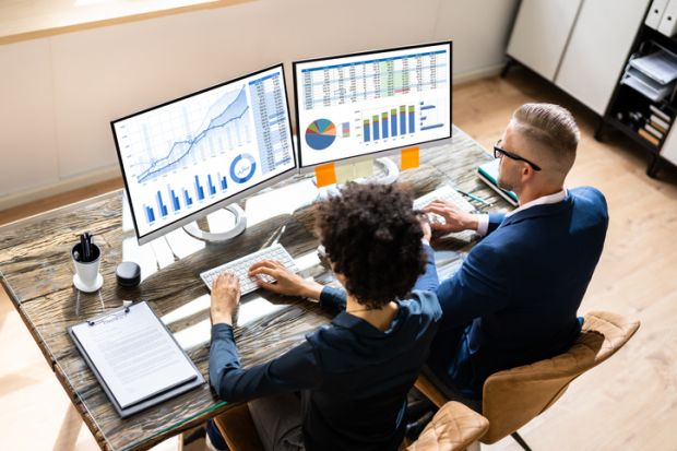 A black woman and a white man examine data charts A black woman and a white man examine data charts
