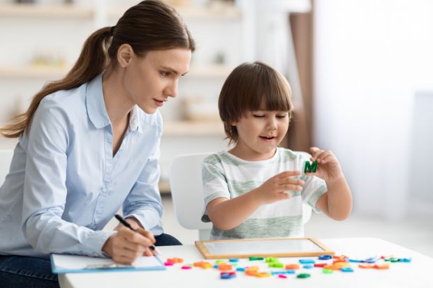 A woman with a clipboard observes a child A woman with a clipboard observes a child