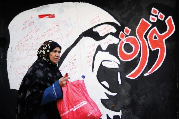 Egyptian woman walks past 'Revolution' graffiti, American University in Cairo Egyptian woman walks past 'Revolution' graffiti, American University in Cairo