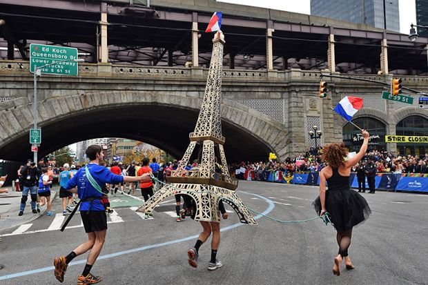 A runner carries a model of the Eiffel Tower during the New York City Marathon in New York, USA. To illustrate that European governments and institutions are launching schemes to attract US talent.