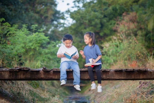 Two children read books on a bridge, symbolising humanities students becoming engineers