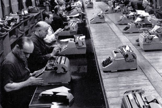 Men typing in a row in a factory Men typing in a row in a factory