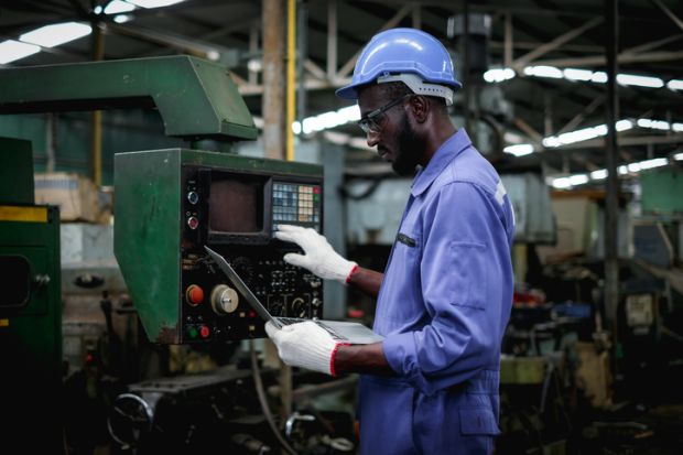 factory worker in using laptop and push buttons to test the machine operation after maintenance