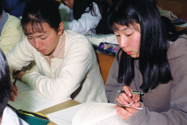 Female Japanese students reading textbooks Female Japanese students reading textbooks
