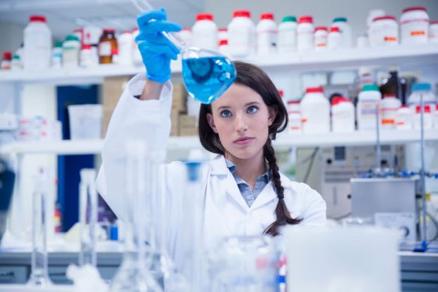 Female scientist examining liquid in flask Female scientist examining liquid in flask