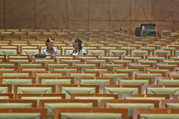 Female students chatting in empty lecture hall