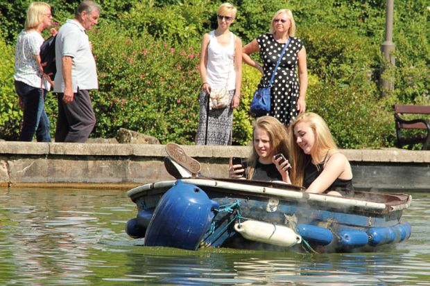Female students using smartphones on boating lake Female students using smartphones on boating lake
