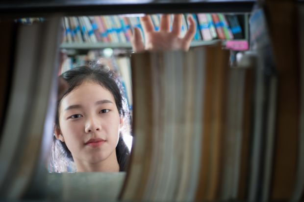 Female student holding book in library